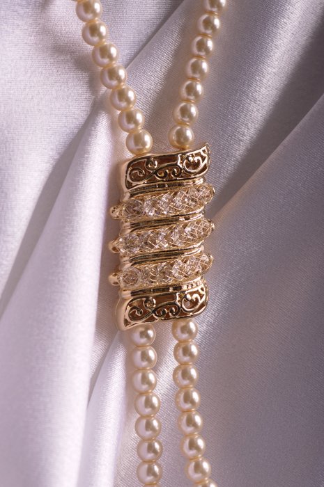 жемчужное ожерелье на шелковом фоне с золотой медалью