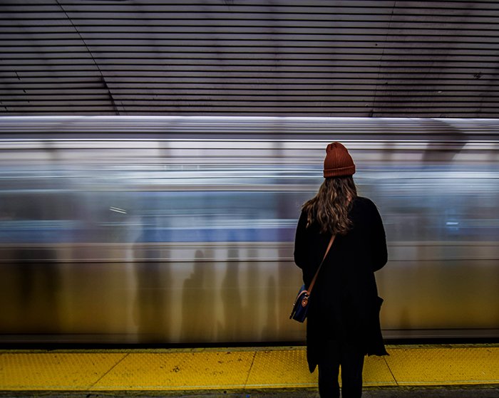 Женщина стоит перед движущимся поездом