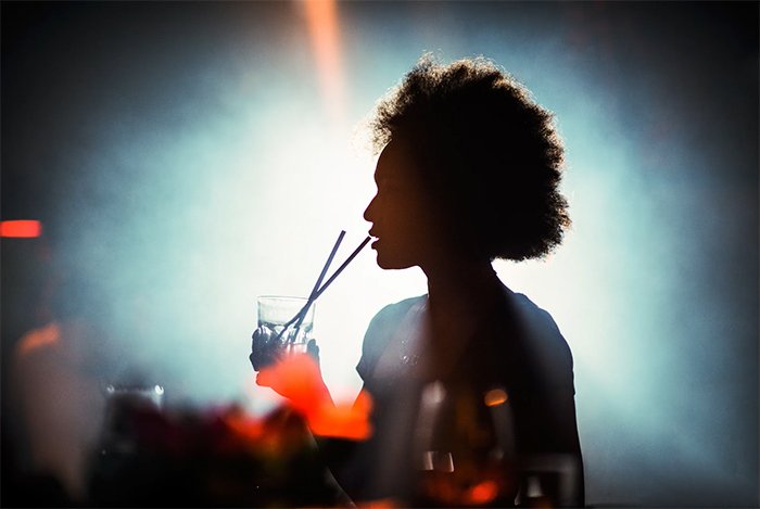 Силуэт женщины, пьющей с соломинкой в ночном клубе
