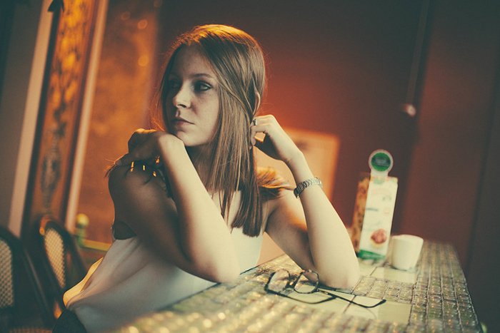 Портретная фотография девушки, сидящей за столом в вольфрамовом свете
