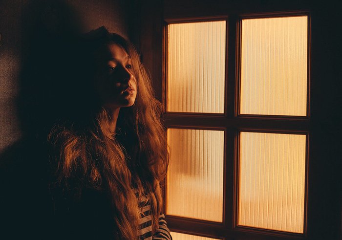 Портретная фотография девушки у окна в вольфрамовом свете