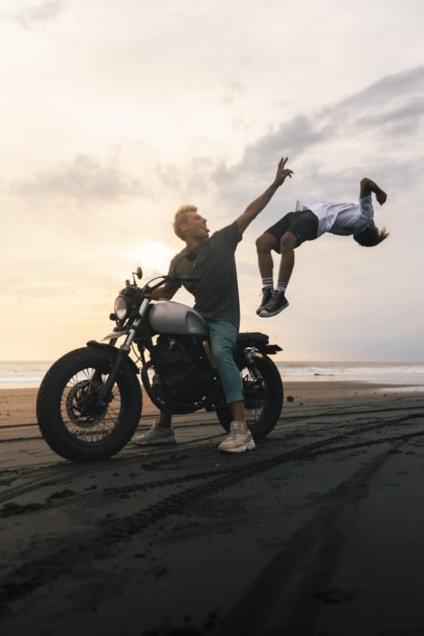 Фотография парня на мотоцикле с прыгающим с него мальчиком