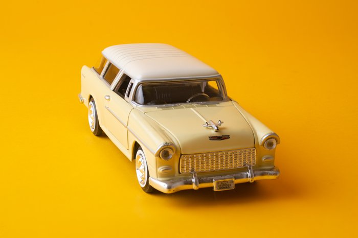 Четкое изображение игрушечного автомобиля на желтом фоне