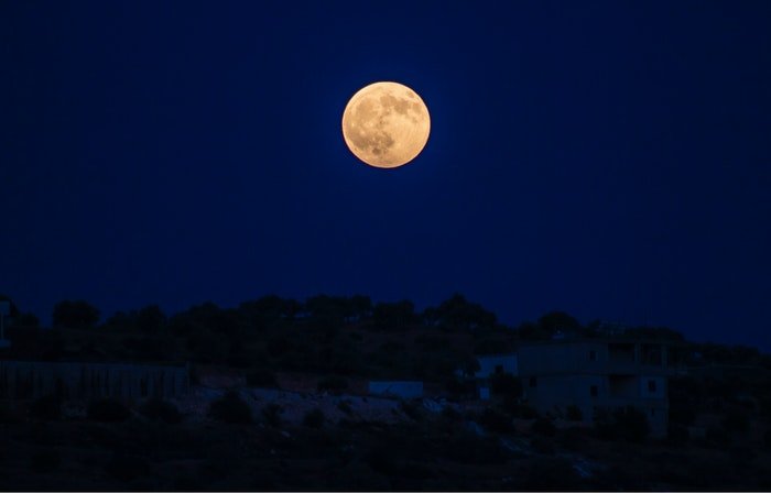Фотография полной луны над ночным городом