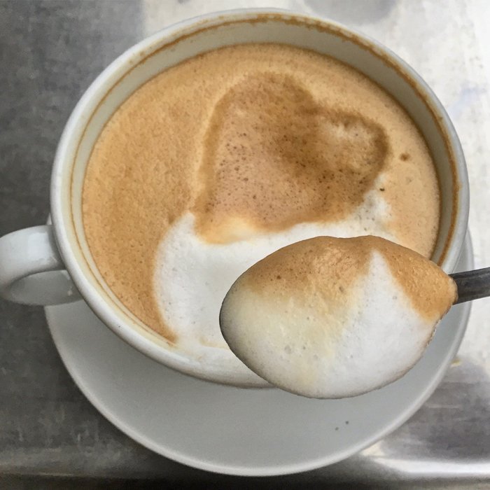 Close up of spooning coffee foam from the cappuccino
