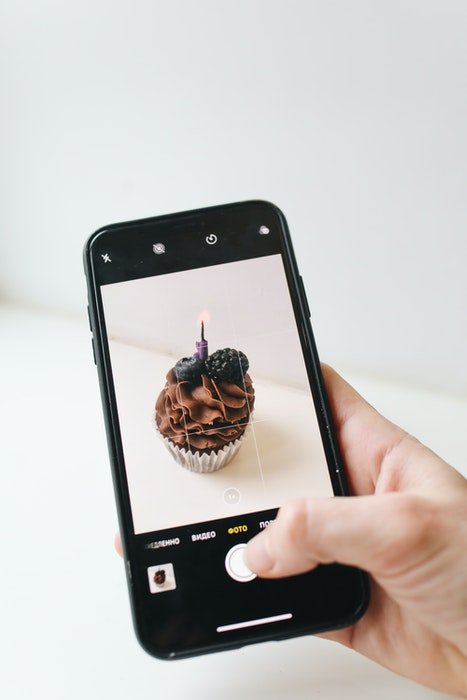 Человек фотографирует шоколадный кекс на камеру iphone