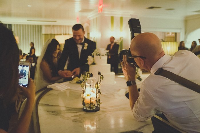 Свадебный фотограф снимает портрет счастливой пары, разрезающей торт