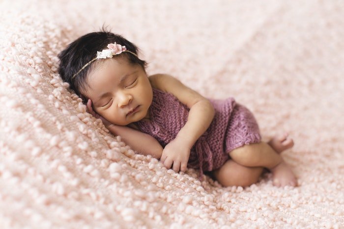 Милая новорожденная девочка на розовом одеяле