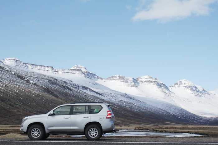Фотография серебристого автомобиля с горами на заднем плане
