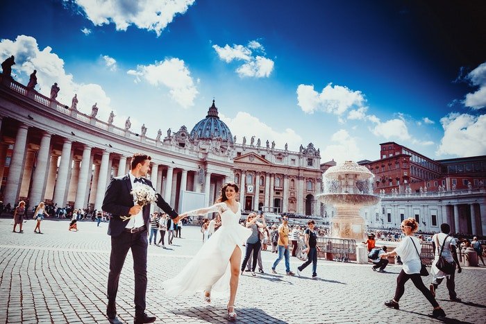 Свадебный портрет молодоженов, идущих рука об руку по открытой площади