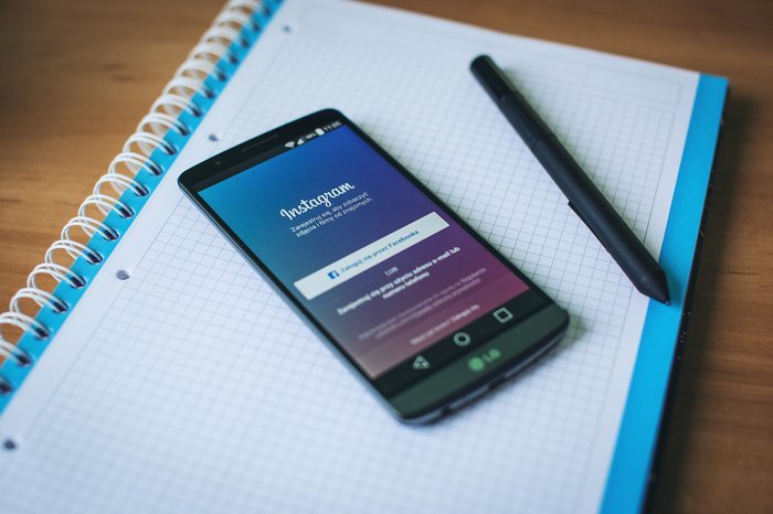 Смартфон, открытый в Instagram, поверх ноутбука