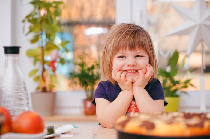 Милый жизненный портрет маленькой девочки за кухонным столом