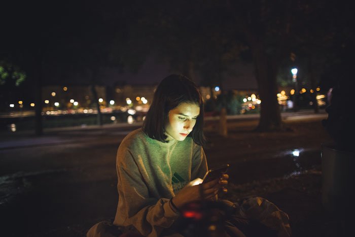 Девушка пользуется смартфоном на крыше ночного города