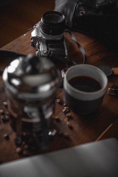 Фотография фотоаппарата и кружки кофе на деревянном столе