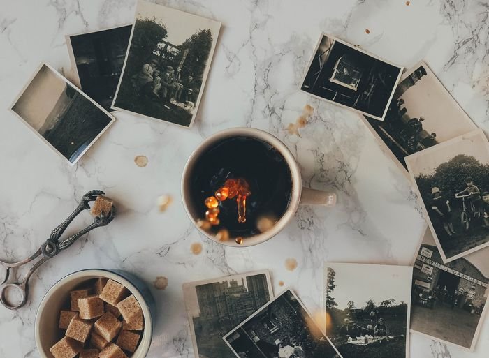 Coffee Splash Photography: накладная фотография кофейной кружки на столе с черно-белыми полароидными фотографиями