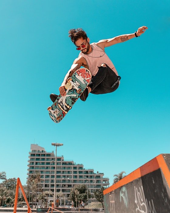 фото прыгающего скейтбордиста на фоне голубого неба
