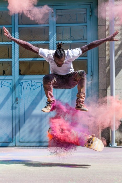 фото скейтбордиста, выполняющего трюк с цветным порошком