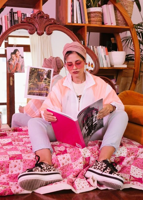 изображение женщины, сидящей на полу и читающей журнал в солнцезащитных очках oink