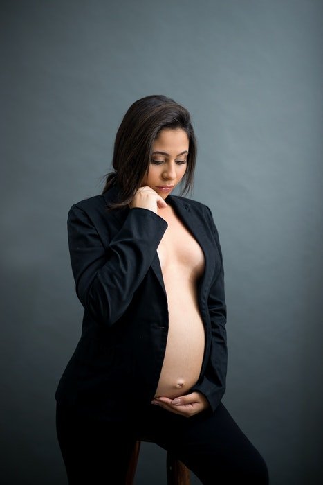 Красивое будуарное фото беременной женщины, позирующей в студии