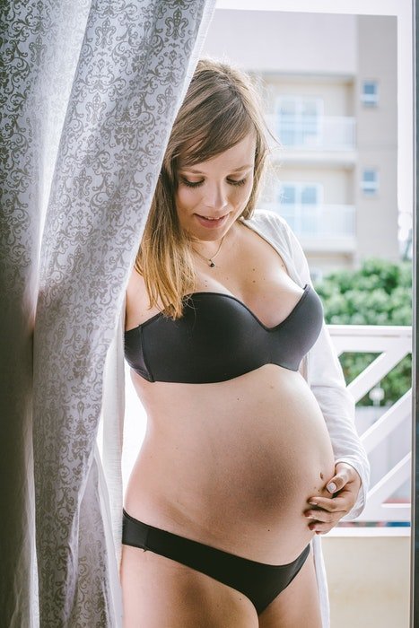 Красивое будуарное фото беременной женщины, позирующей в нижнем белье