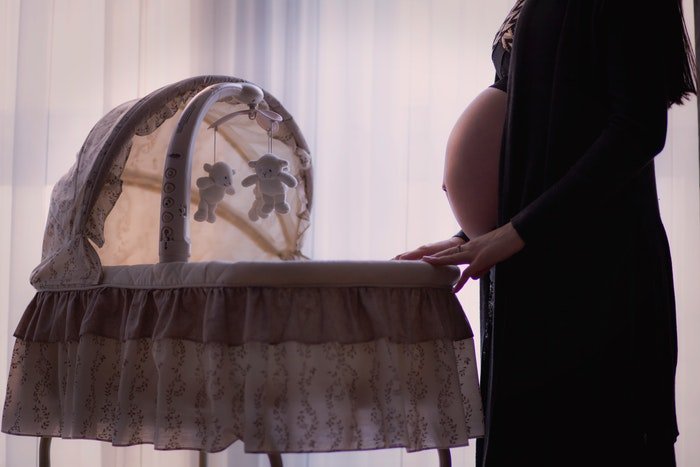Красивое будуарное фото беременной женщины, качающей колыбель