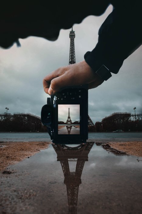 Человек фотографирует Эйфелеву башню