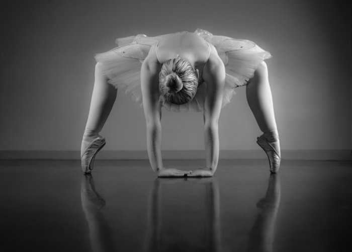 Грациозная балерина разминается в черно-белой балетной студии