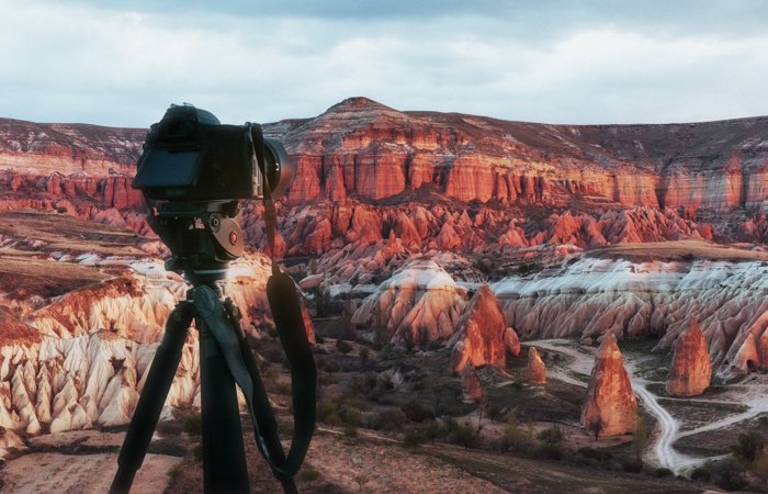 Красивый закат над каньоном в турции в каппадокии с зеркальной камерой на штативе на переднем плане