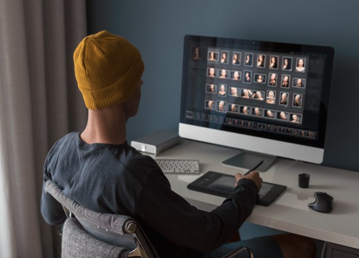 Мужчина работает дома, редактируя фотографии с помощью пресетов Lightroom на компьютере