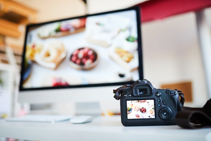 Фоновое изображение фотоаппарата с фотографией еды на столе на фоне компьютера с программой редактирования