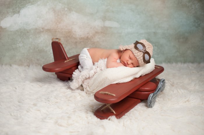 новорожденный ребенок позирует на интересном пропеллере самолета