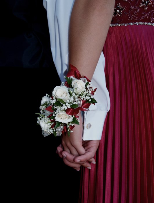 снимок выпускной пары, держащейся за руки сзади