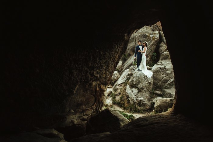 свадебная фотография пары, стоящей у входа в пещеру