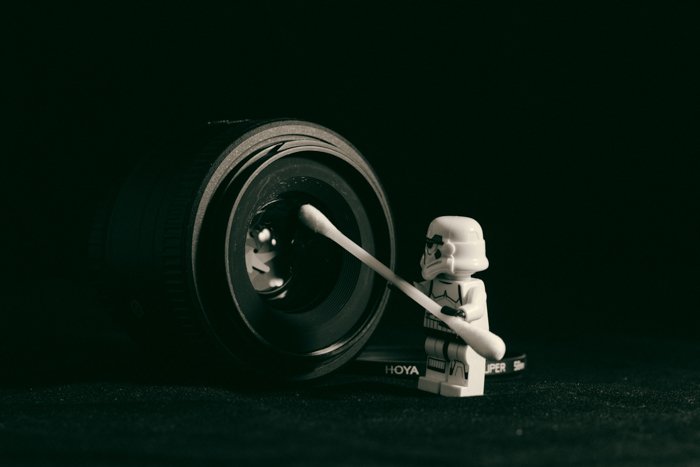 A lego figure cleaning a camera lens