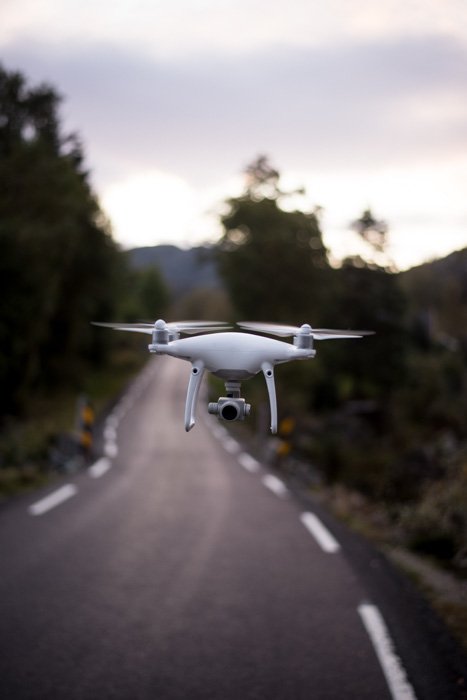 изображение летающего дрона над дорогой