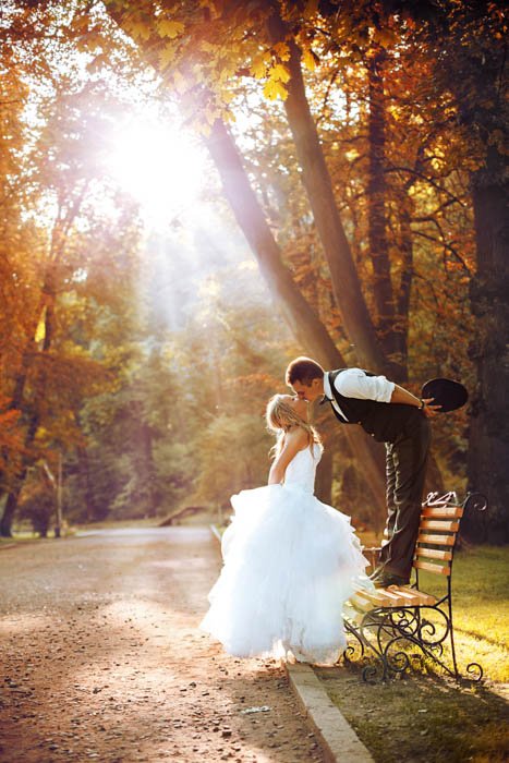 Нетипичное изображение жениха, стоящего на скамейке и целующего невесту