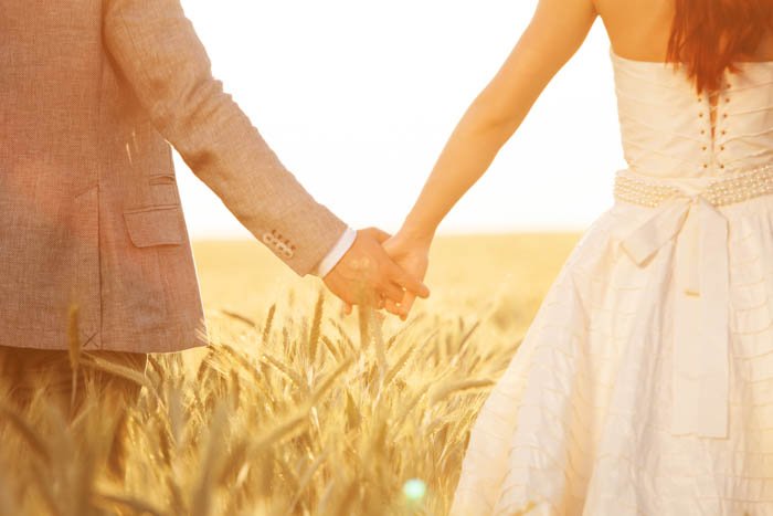 Фотография жениха и невесты, держащих друг друга за руку