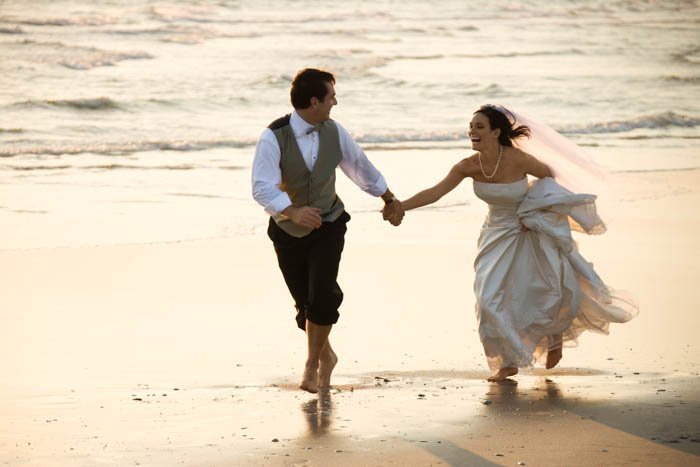 Изображение жениха и невесты, бегущих по пляжу