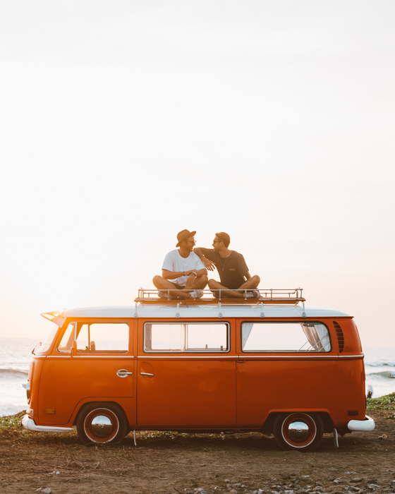 изображение двух друзей, сидящих на вершине оранжевого автобуса volkswagen