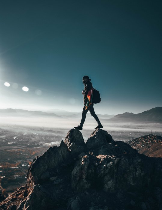 изображение человека, стоящего на вершине горы