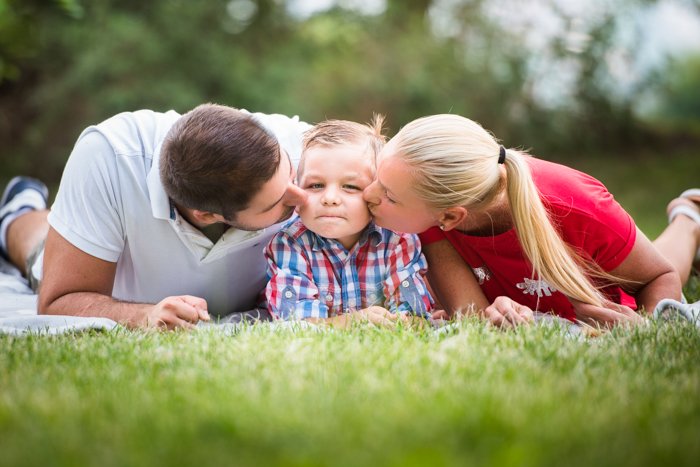 семейный портрет позирует мать отец и ребенок, лежа в траве