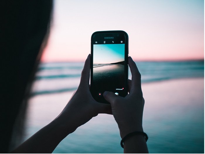 человек фотографируется со смартфона на пляже