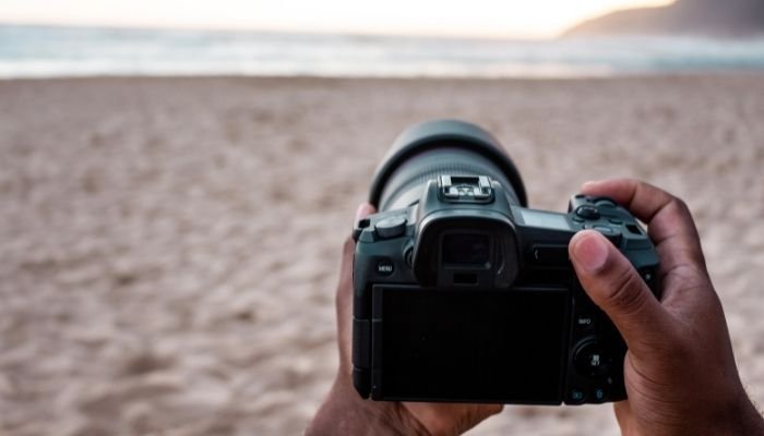 человек держит камеру dslr на пляже