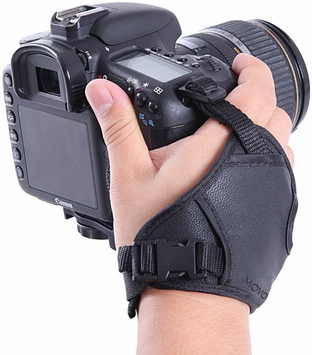 Крупный план руки, держащей DSLR камеру с наручным ремешком