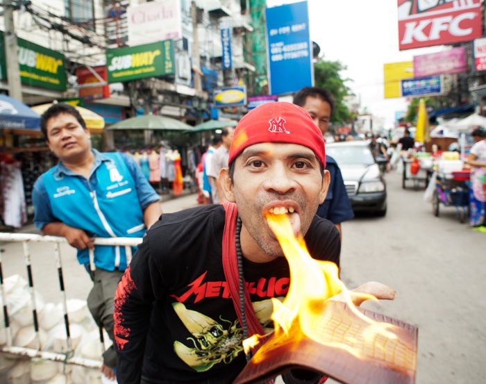 Экологическая портретная фотография уличного торговца в Бангкоке, демонстрирующего огнеупорное изделие из крокодиловой кожи
