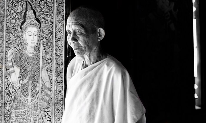 Черно-белый экологический портрет буддийской монахини с резным рельефом на заднем плане