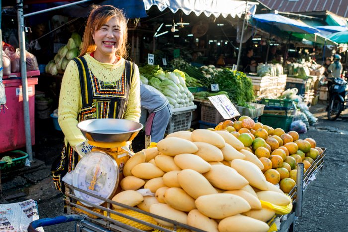 Экологический портрет продавца манго, стоящего у своего рыночного прилавка в Таиланде