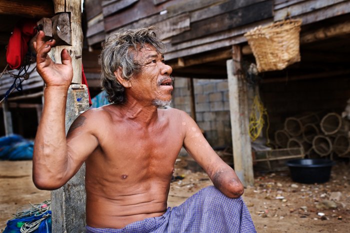 Экологическая портретная фотография мужчины из племени морских цыган мокен на юге Таиланда, рассказывающего нам историю о том, как он потерял руку. 
