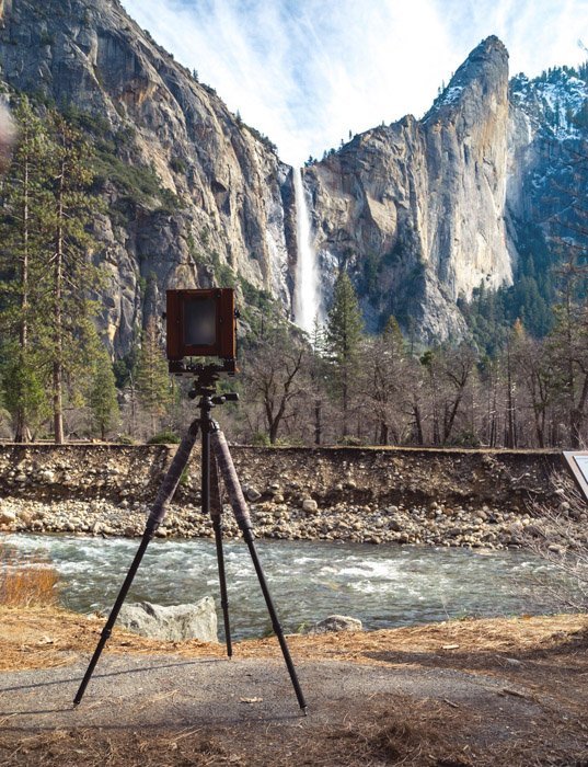 кинокамера на фоне горной сцены с водопадом
