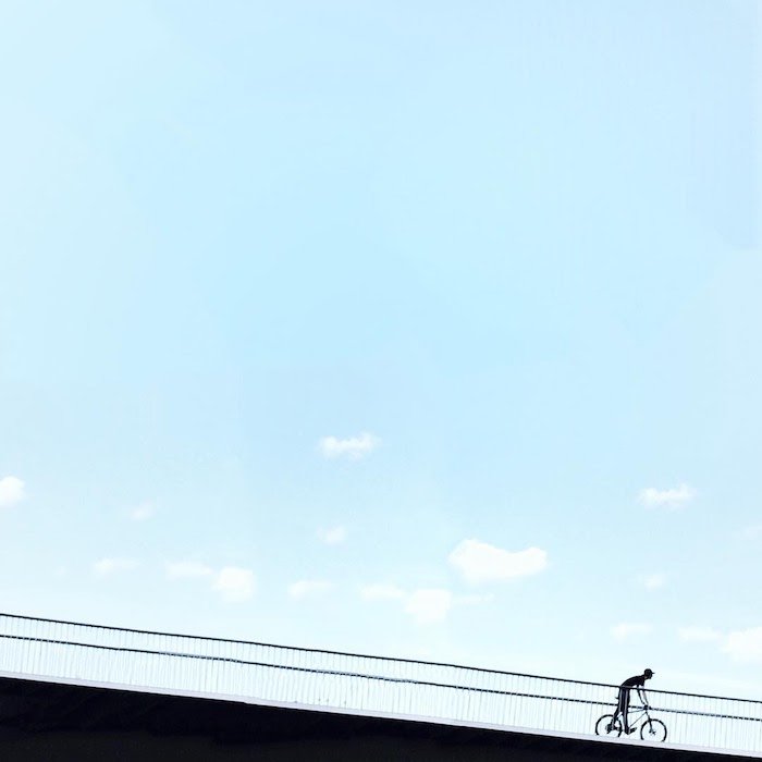 Минималистская фотография велосипедиста на мосту